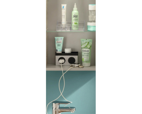 Organisierter Badezimmerschrank mit Kosmetikprodukten, einer Steckdoseneinheit mit Ladekabel für eine Smartwatch und einem Wasserhahn.