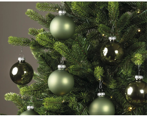 Weihnachtskugeln in verschiedenen Grüntönen, matt und glänzend, hängend an einem grünen Weihnachtsbaum.