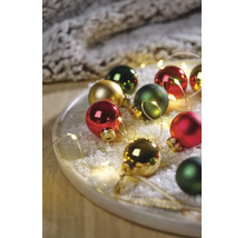 Festliches Arrangement aus Weihnachtsbaumkugeln in Rot, Grün und Gold auf einem Tablett mit Kunstschnee und LED-Lichterkette.