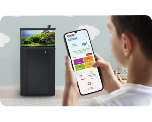 Eine Person steuert eine Eheim Aquarienkombination mit der Eheim Digital App auf einem Smartphone in einem hellen Raum.