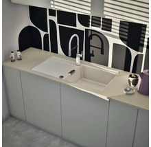 Einbauspüle mit Abtropffläche und Küchenarmatur in einer modernen Küche mit geometrischer Rückwand und hellen Unterschränken.