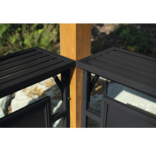 Detailansicht eines schwarzen Metallzauns mit horizontalen Lamellen, montiert an einem quadratischen Holzpfosten im Garten.