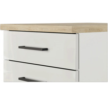 Nahaufnahme einer weißen Kommode mit Schubladen, schwarzen Griffen und einer Arbeitsplatte in Eichenoptik.