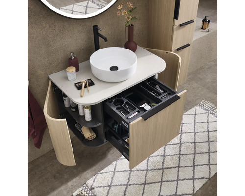 Moderner Badezimmer-Waschtisch in Holzoptik mit rundem Aufsatzbecken, schwarzer Armatur und geöffneter Schublade mit Inneneinteilung.