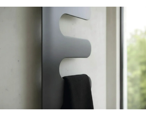 Moderner Design-Heizkörper in Dunkelgrau mit einem schwarzen Handtuch an der Wand.