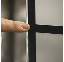 Detailaufnahme einer Glaswand mit schwarzem Gittermuster und mattiertem Glas, ein Finger zeigt auf die Glaskante.