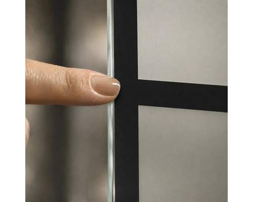 Detailaufnahme einer Glaswand mit schwarzem Gittermuster und mattiertem Glas, ein Finger zeigt auf die Glaskante.