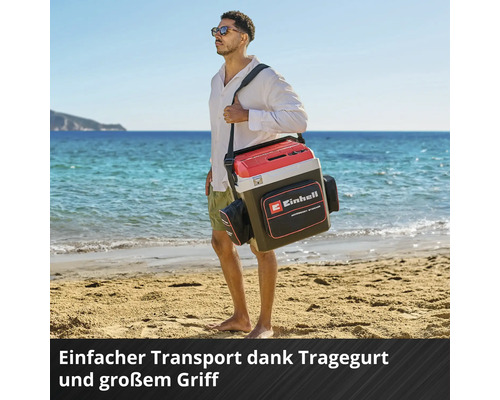 Einhell Kühlbox mit Tragegurt, großem Griff und Zubehörtasche, getragen von einem Mann an einem hellen Sandstrand.