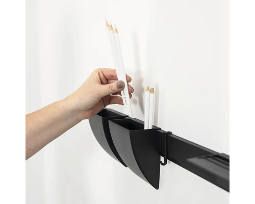 Hand legt einen Stift in einen an einer Wandleiste befestigten Aufbewahrungsbecher zur Organisation von Schreibwaren oder Werkzeugen.