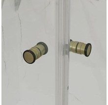 Zylindrische Türgriffe in Goldoptik mit schwarzen Details an einer gläsernen Duschwand vor einer marmorierten Wand.