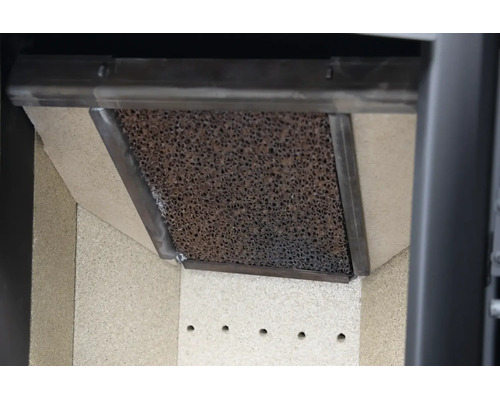 Nahaufnahme eines Katalysator-Filters in einem Kaminofen mit poröser Oberfläche, Metallrahmen und Brennraumauskleidung.