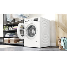 Bosch Waschmaschine mit offener Tür in einem modernen Hauswirtschaftsraum mit Regalsystem und Wäschekorb.