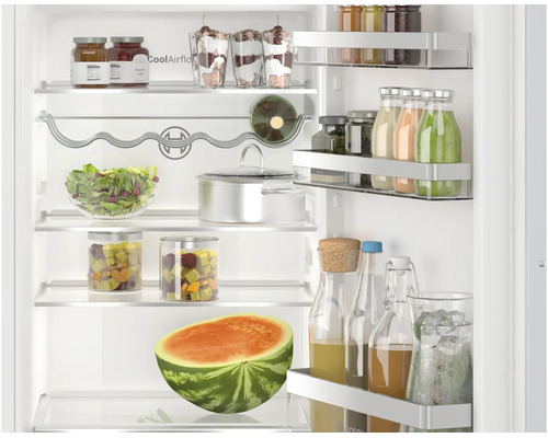 Innenansicht eines Bosch Kuehlschranks mit Glasablagen, Flaschenablage, Tuerabstellern und mit Lebensmitteln befuellten Glaesern sowie Wassermelone.