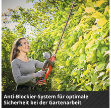 Eine Frau mit Schutzbrille schneidet eine Hecke mit einer Akku-Heckenschere von Einhell.