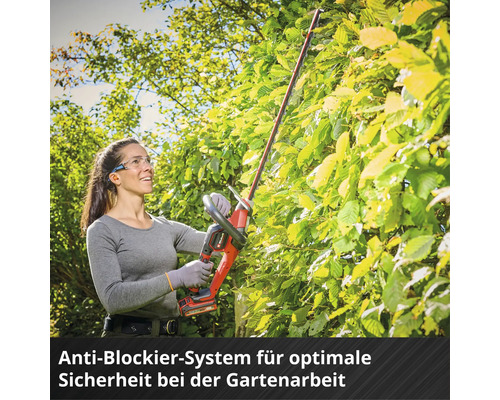 Eine Frau mit Schutzbrille schneidet eine Hecke mit einer Akku-Heckenschere von Einhell.