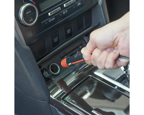 Eine Hand steckt einen 12-Volt-Kfz-Stecker in den Zigarettenanzünder eines Autos.