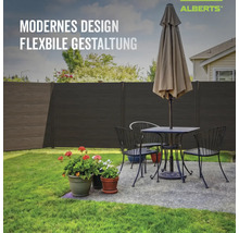 Moderner Alberts Sichtschutzzaun in dunkler Holzoptik im Garten hinter einer gemütlichen Sitzecke mit Blumen.