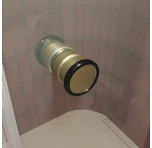 Ein in die Wand eingelassenes Wannen- oder Duschanschlussstück aus Metall mit Dichtungsring vor einer gefliesten Wand.