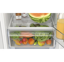 Innenansicht eines Kühlschranks mit einem transparenten MultiBox XXL Gemüsefach gefüllt mit frischem Obst und Gemüse.