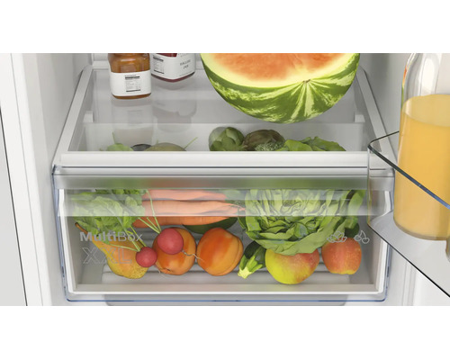 Innenansicht eines Kühlschranks mit einem transparenten MultiBox XXL Gemüsefach gefüllt mit frischem Obst und Gemüse.