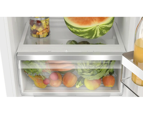 Innenansicht eines Kuehlschranks mit gefuellter VitaFresh XXL Gemueseschublade und Glasablage mit Lebensmitteln.