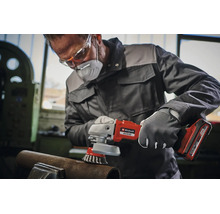 Handwerker mit Schutzkleidung nutzt einen Einhell Akku Winkelschleifer mit Drahtbürstenaufsatz zur Metallbearbeitung an einem Werkstück.