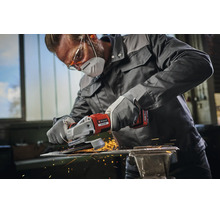 Handwerker mit Schutzkleidung nutzt einen Einhell Akku Winkelschleifer um ein Metallstück in einer Werkstatt zu bearbeiten mit Funkenflug.