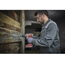 Ein Handwerker nutzt einen Akku Bohrschrauber von Einhell, um eine Schraube in eine Holzwand zu drehen.