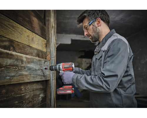 Ein Handwerker nutzt einen Akku Bohrschrauber von Einhell, um eine Schraube in eine Holzwand zu drehen.