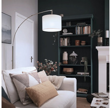 Moderne Bogenlampe mit Stoffschirm und Metallgestell in einem gemütlich eingerichteten Wohnzimmer mit Bücherregal und Kamin.