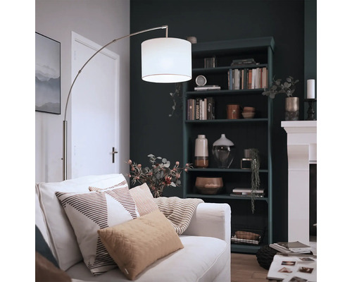 Moderne Bogenlampe mit Stoffschirm und Metallgestell in einem gemütlich eingerichteten Wohnzimmer mit Bücherregal und Kamin.