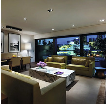 Modernes Wohnzimmer mit Sofas, Marmor Couchtisch und Blick auf ein Kreuzfahrtschiff in der nächtlichen Stadt bei moderner Innenbeleuchtung.