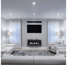 Modernes Wohnzimmer mit flachem Wandkamin aus Metall, montiertem Fernseher, bequemen Ledersofas und hellem Teppich in einem organisierten Raum.