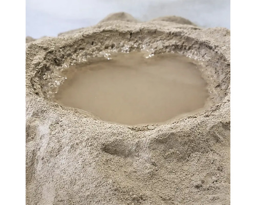 Ein Haufen aus trockenem Baustoffpulver mit einer Mulde in der Mitte, in der sich Wasser befindet, um den Mischvorgang vorzubereiten.