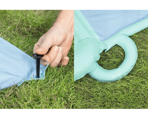 Person befestigt ein aufblasbares Produkt mit einem Bodenanker im Rasen, daneben ist eine aufblasbare Öse im Gras zu sehen.