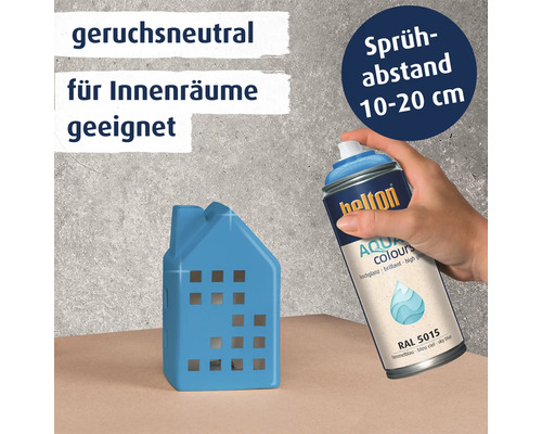 Eine Hand sprüht mit Helton Aqua Colours Lack in Himmelsblau auf ein kleines Deko Haus.