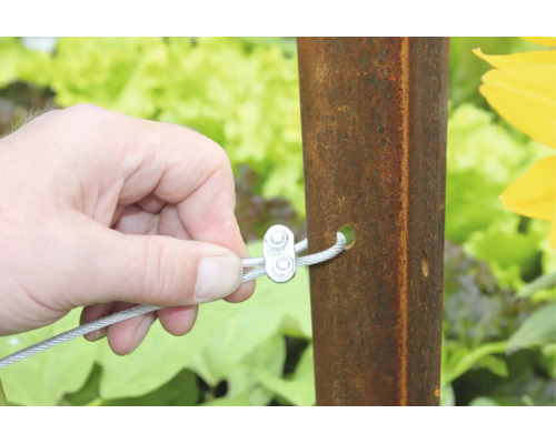 Hand befestigt Drahtseil mit Drahtseilklemme an einem Metallpfosten im Garten.