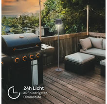 Moderne Outdoor Stehlampe auf einer Terrasse neben einem Gasgrill und Lounge Möbeln mit einer Laufzeit von 24 Stunden bei niedrigster Dimmstufe.