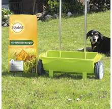 Solabiol Herbstrasendünger 10 Kilogramm Sack neben einem Streuwagen auf einer Wiese mit Hund im Hintergrund.