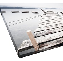 Leinwandbild eines Sees mit einem alten Holzsteg und einigen Booten.