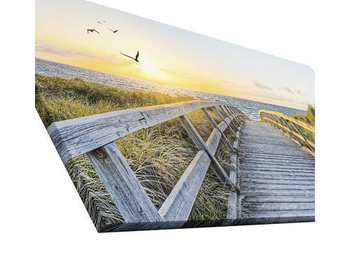 Leinwandbild mit Motiv eines Holzstegs zum Strand bei Sonnenuntergang