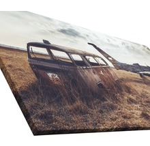 Leinwanddruck mit einer Szene von verlassenen, verrosteten Fahrzeugen in einem Feld.