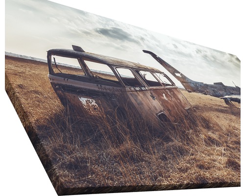Leinwanddruck mit einer Szene von verlassenen, verrosteten Fahrzeugen in einem Feld.