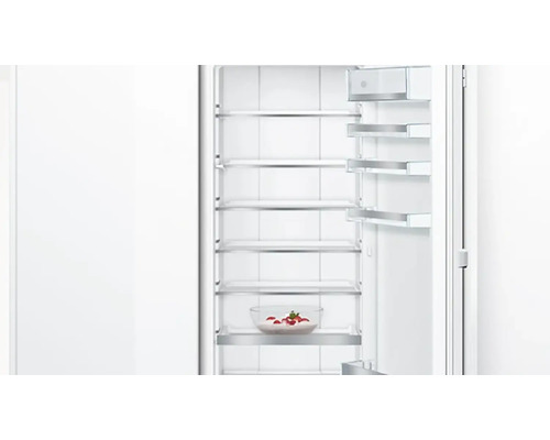 Geöffneter Kühlschrank mit Glasablagen und einer Schüssel mit Erdbeeren