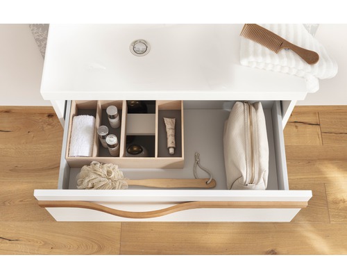 Offene Schublade eines Waschtischunterschranks mit Kosmetikprodukten und Badaccessoires