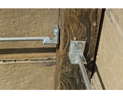 Detailansicht von einem Drahtseilhalter mit Schrauben an einem Holzpfosten befestigt