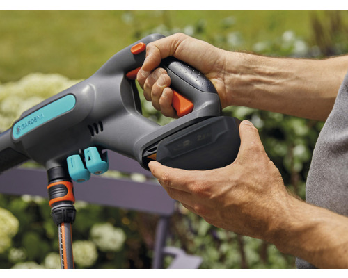 Person setzt Batterie in ein Gardena Gartengerät ein.