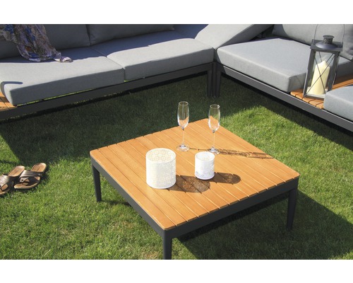 Szene mit Gartenlounge-Möbeln, bestehend aus einem Ecksofa mit grauen Polstern und einem quadratischen Holztisch mit zwei Gläsern und dekorativen Windlichtern