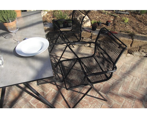 Szene mit zwei schwarzen Seilsesseln und einem Esstisch im Freien
