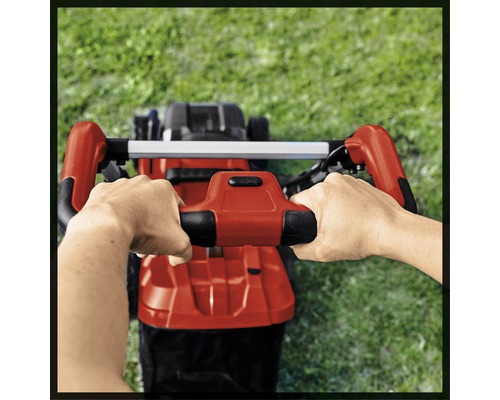 Person bedient Rasenmäher auf Rasenfläche.